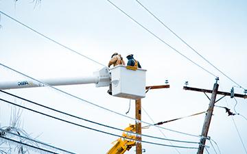 Two men in a bucket truck working on powerlines